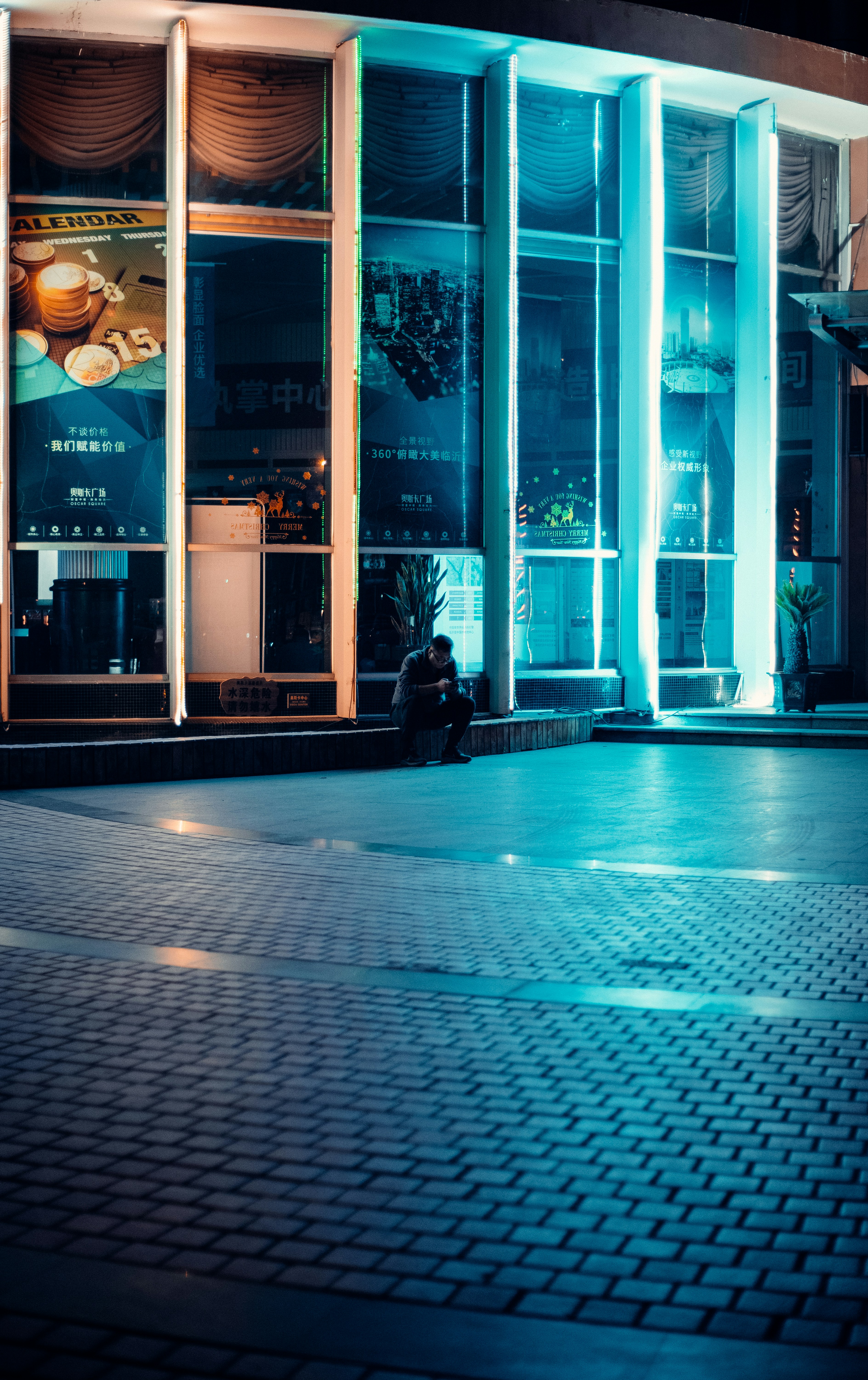 man in black jacket sitting on bench near glass window