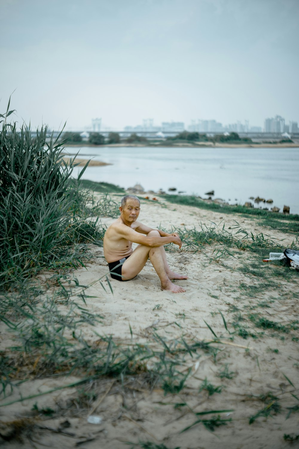 woman in black bikini sitting on gray sand during daytime