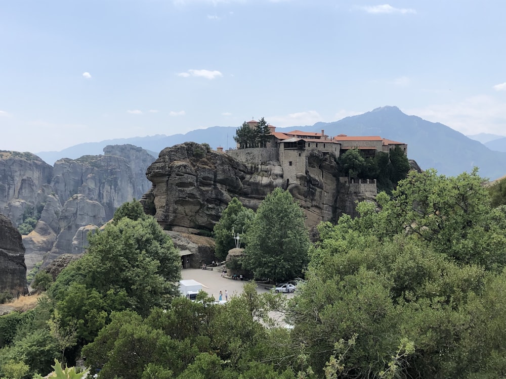 árvores verdes perto da montanha marrom sob o céu azul durante o dia