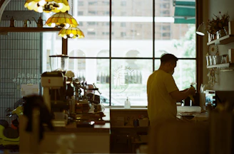 man in white dress shirt standing near glass window