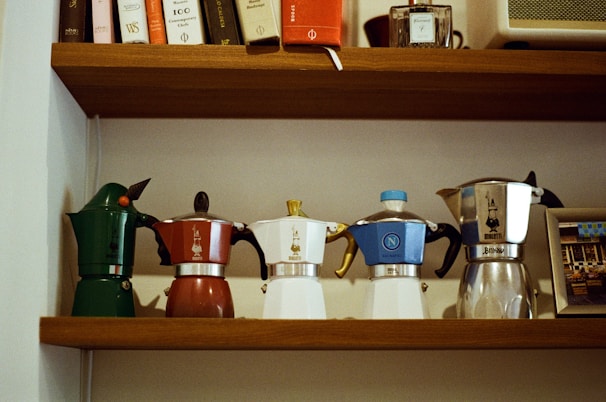 An assortment of colorful coffee jugs arranged on a shelf.