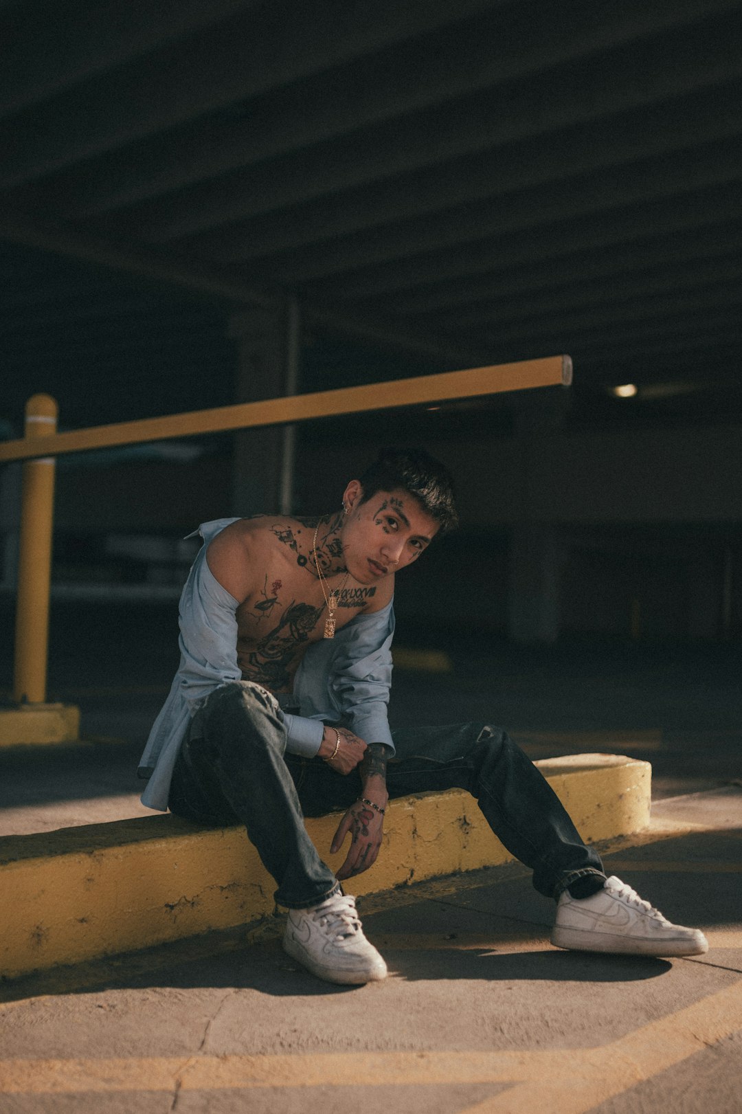 man in white t-shirt and blue denim jeans sitting on brown wooden bench