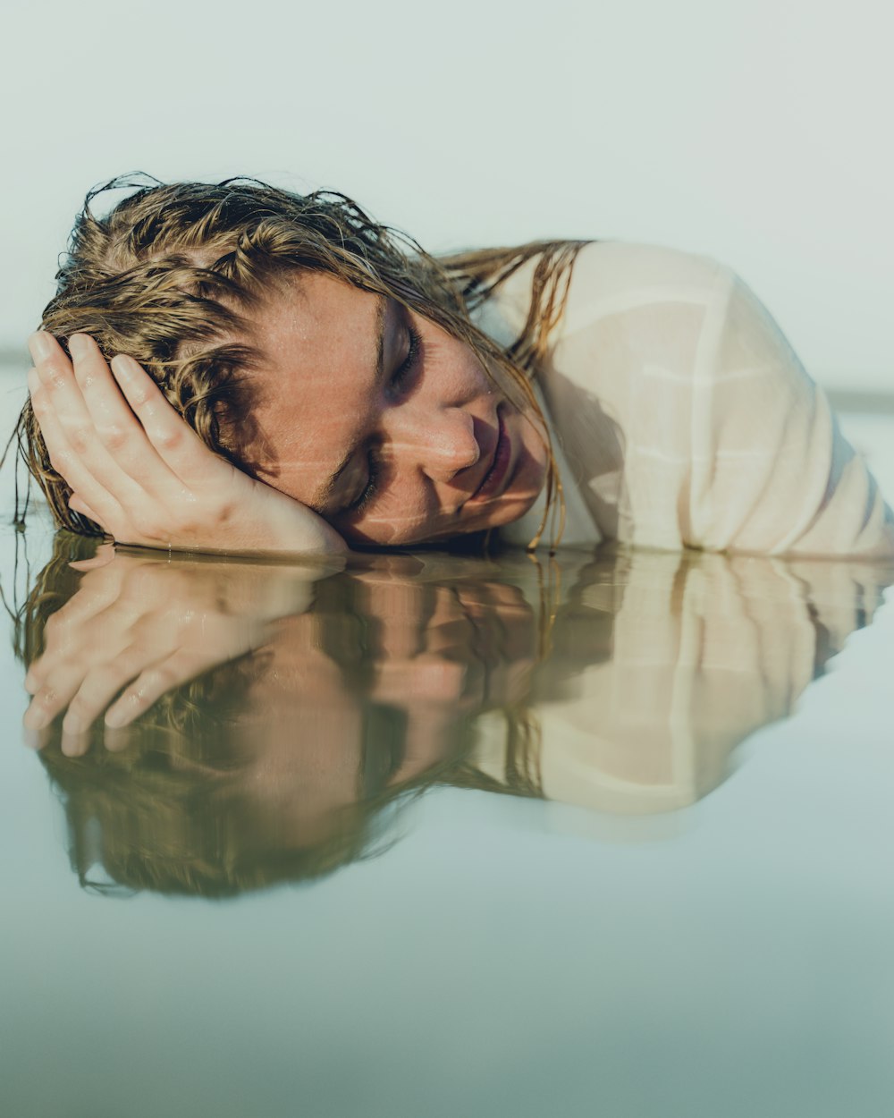 woman in white long sleeve shirt covering her face with her hands