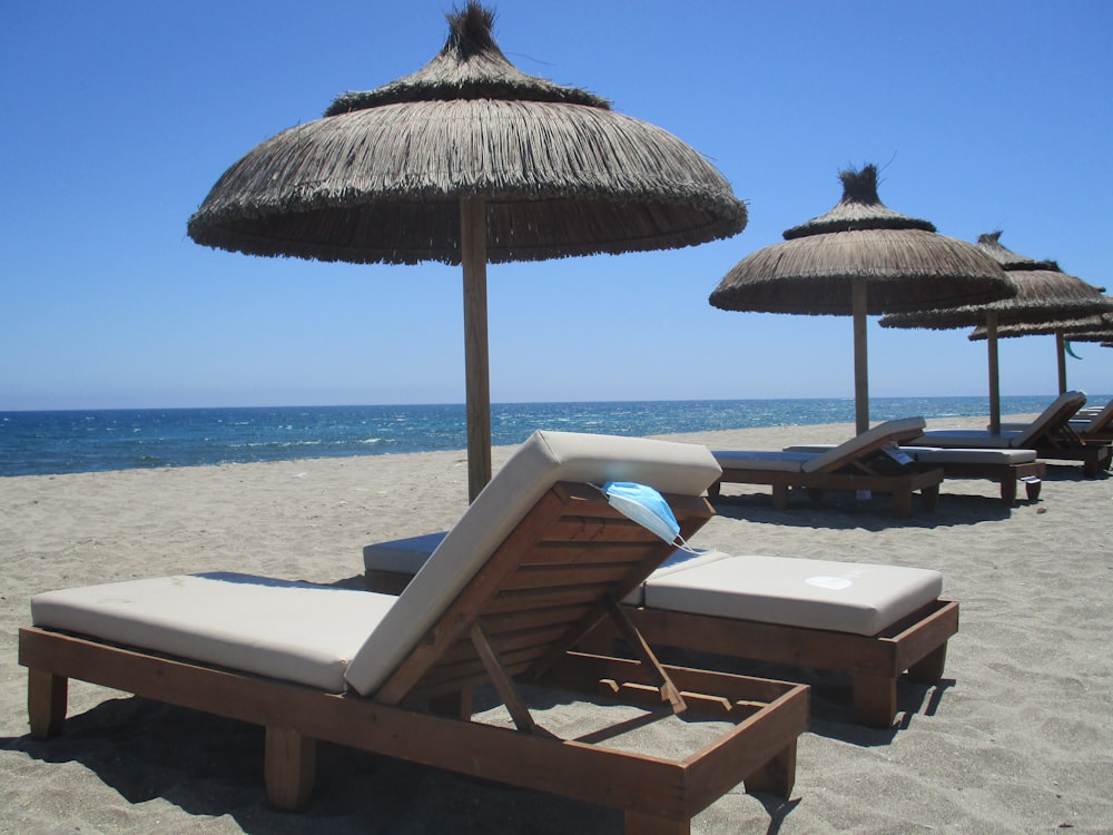 하얀 모래 해변에 갈색 나무 라운지 의자