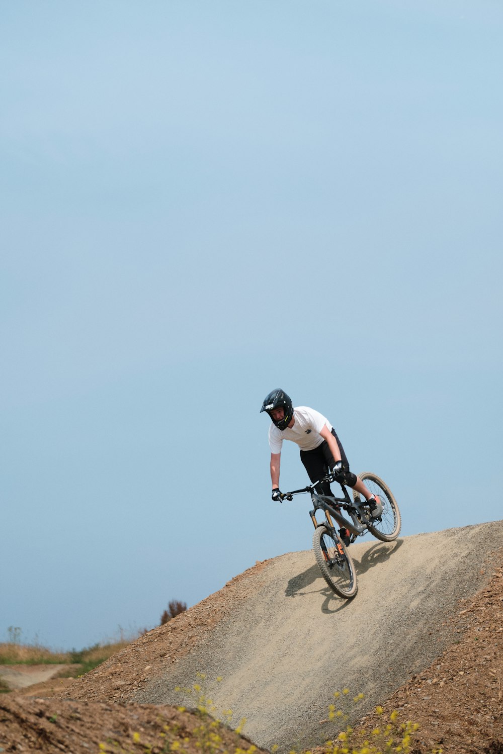 man in white t-shirt riding on black mountain bike on brown rock mountain during daytime