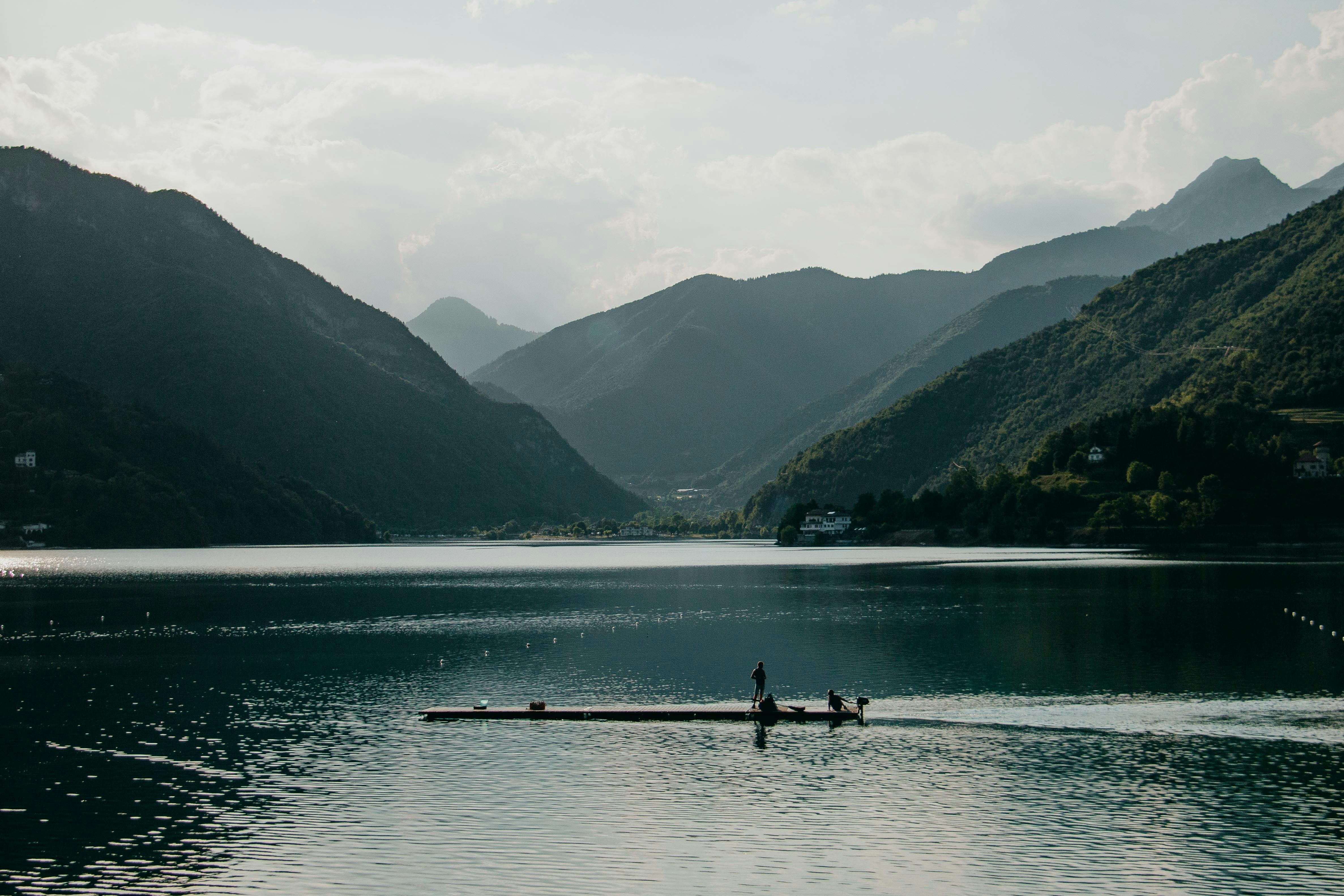 people on dock near mountains during daytime