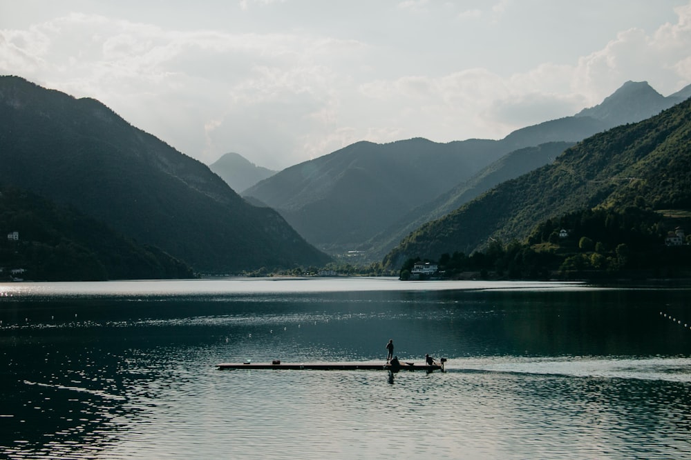 people on dock near mountains during daytime