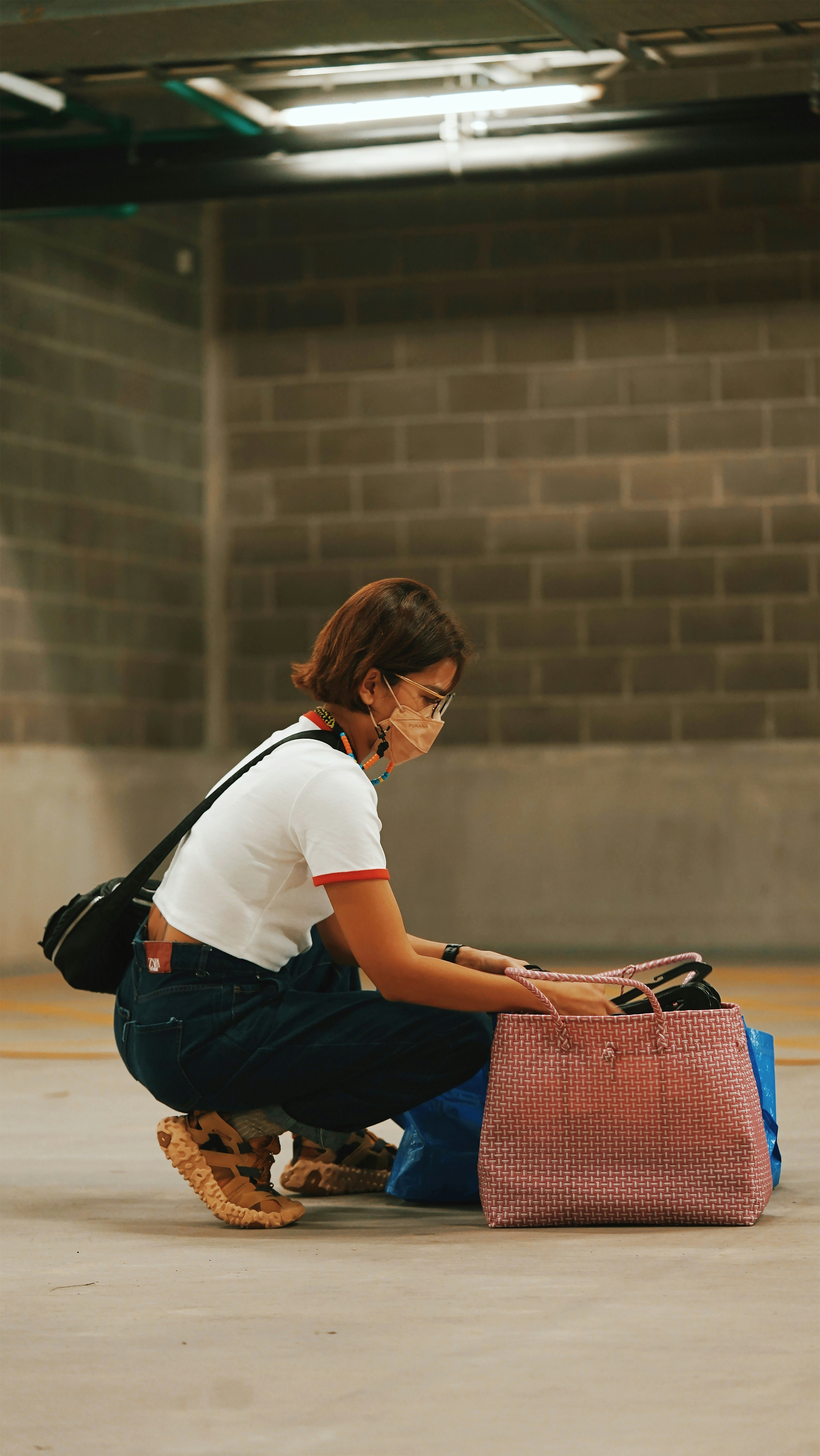 woman in white t-shirt and blue denim jeans sitting on red bench