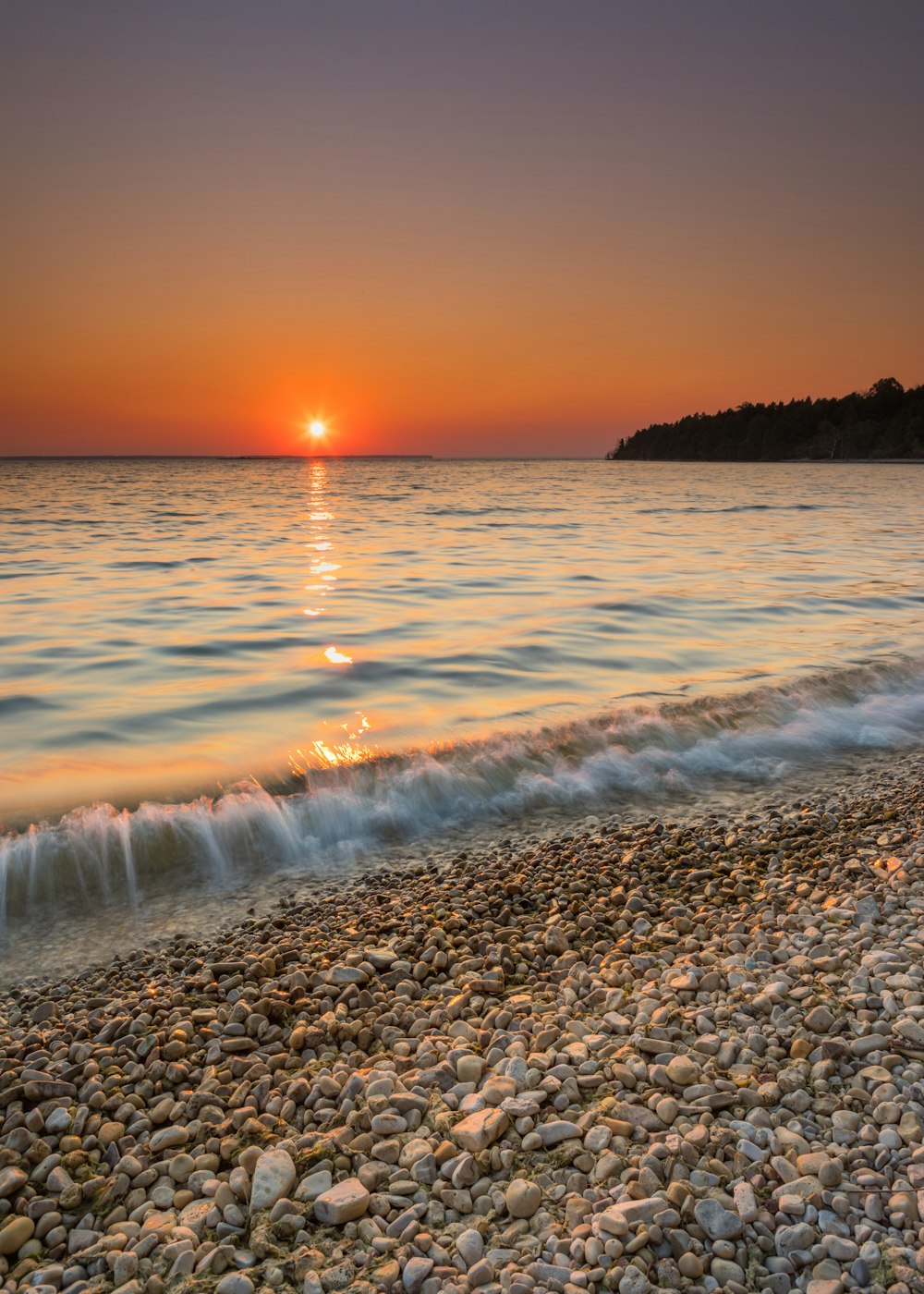 sea waves crashing on shore during sunset