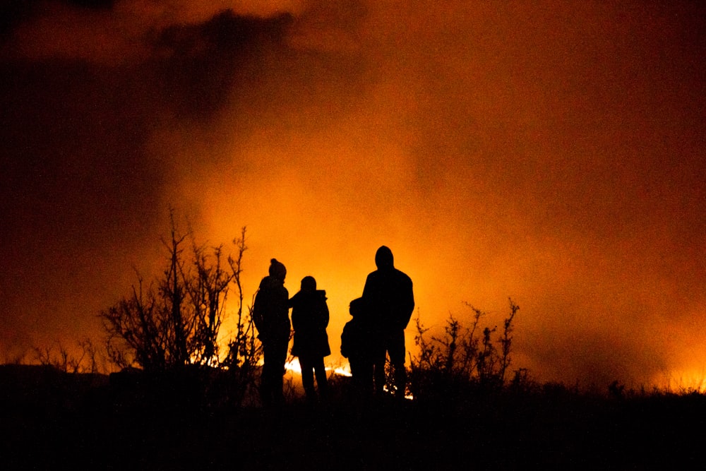 silhueta de 2 pessoas em pé no campo de grama durante o pôr do sol