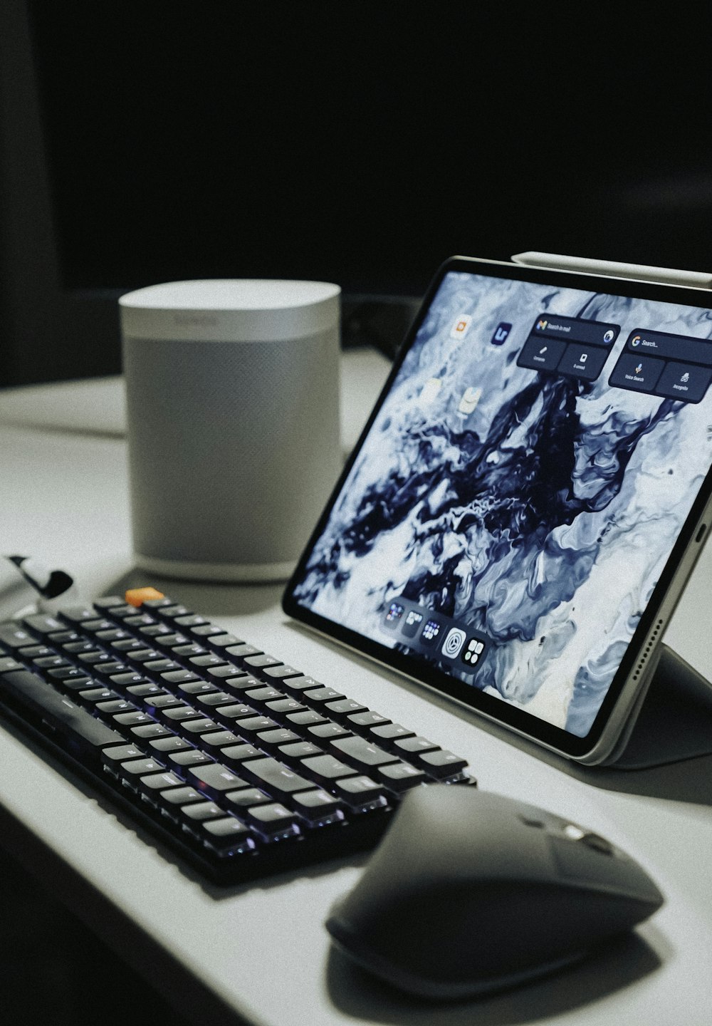 black ipad beside black computer keyboard on white table