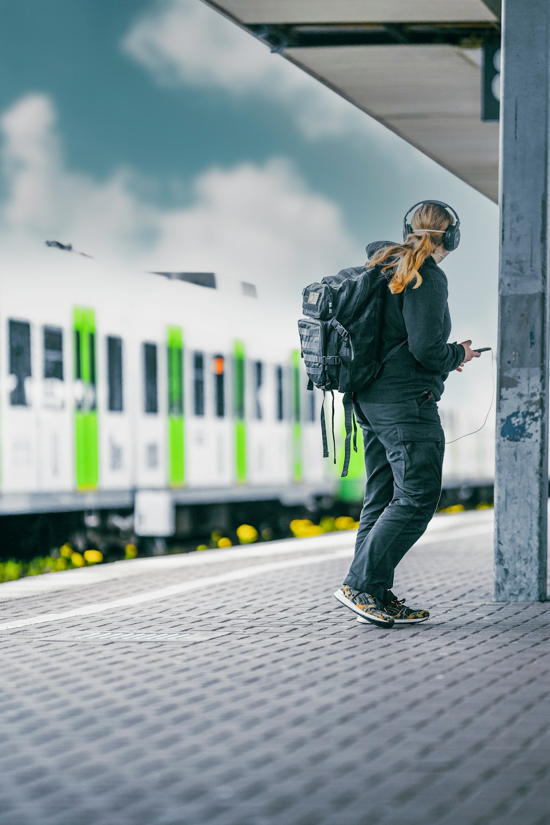 man in black jacket and blue denim jeans standing beside white train during daytime