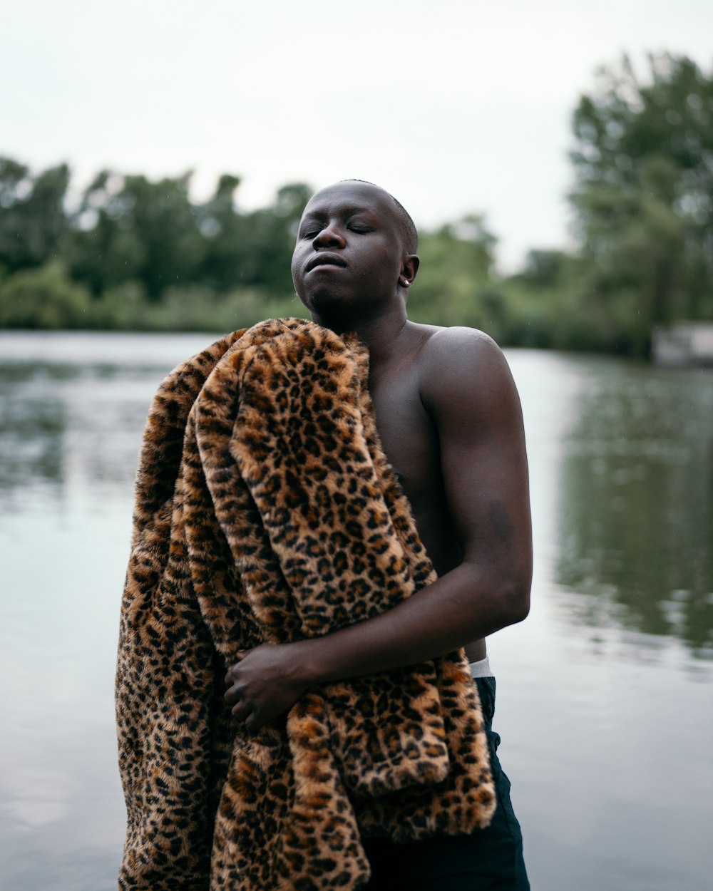 woman in brown and black leopard print scarf standing beside body of water during daytime