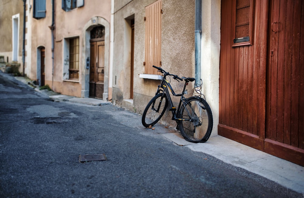 black city bike parked beside brown wooden door