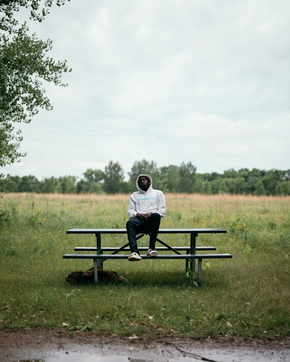 man in white shirt sitting on black wooden bench