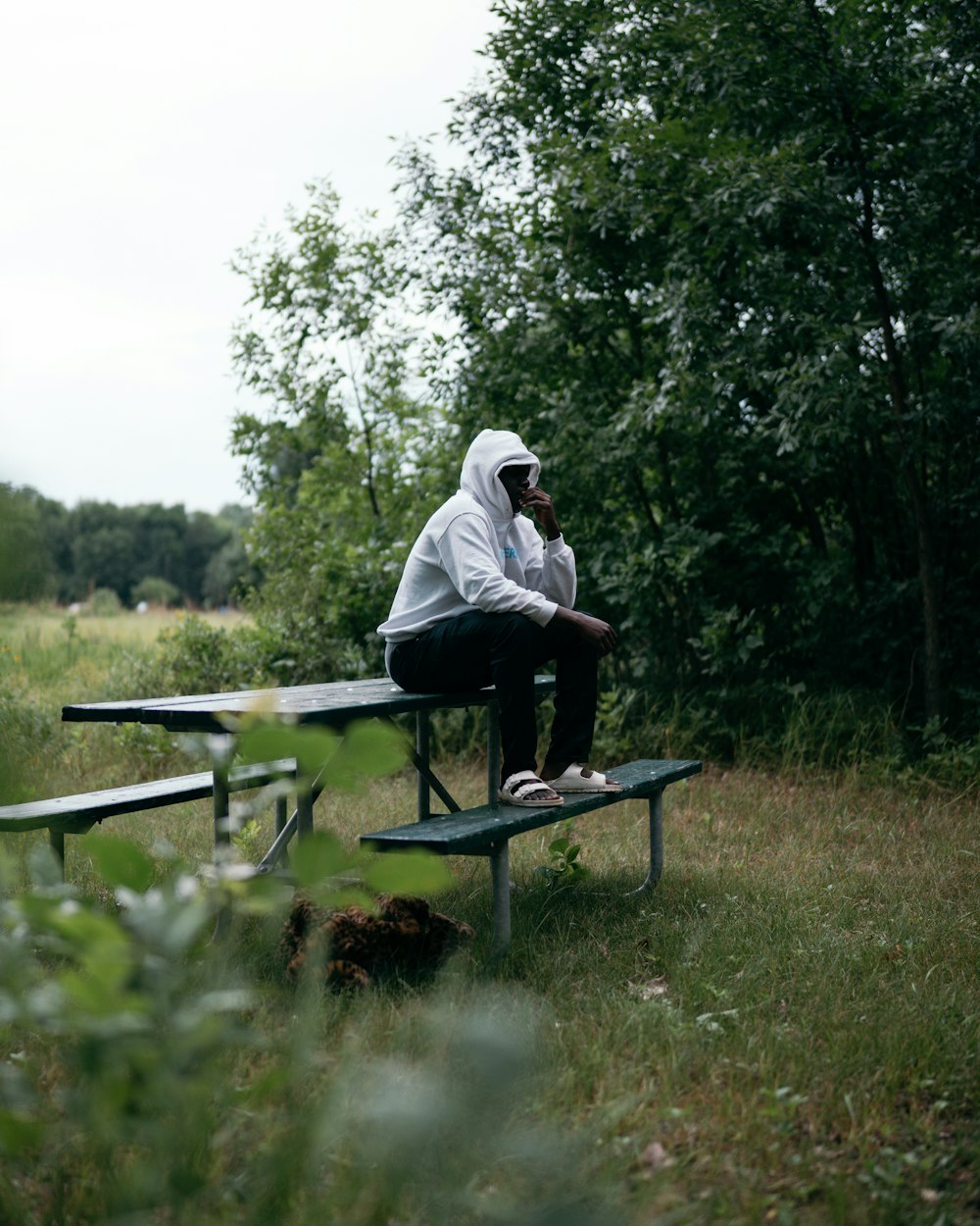 man in white shirt sitting on brown wooden bench during daytime