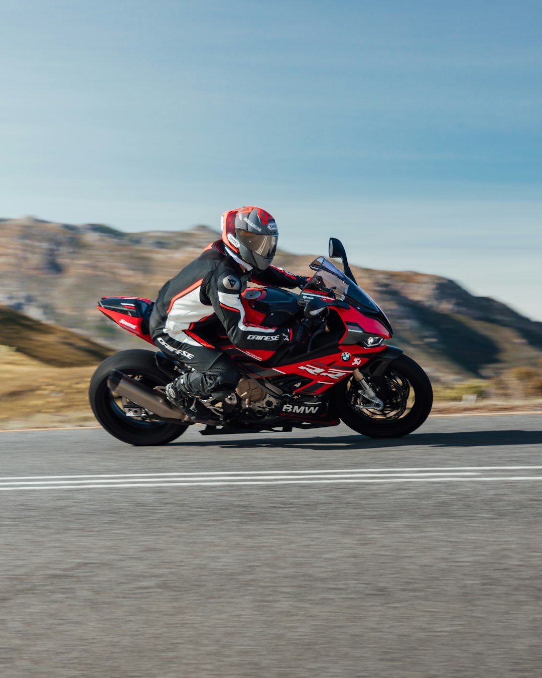 man in black and red motorcycle suit riding on black sports bike on gray asphalt road