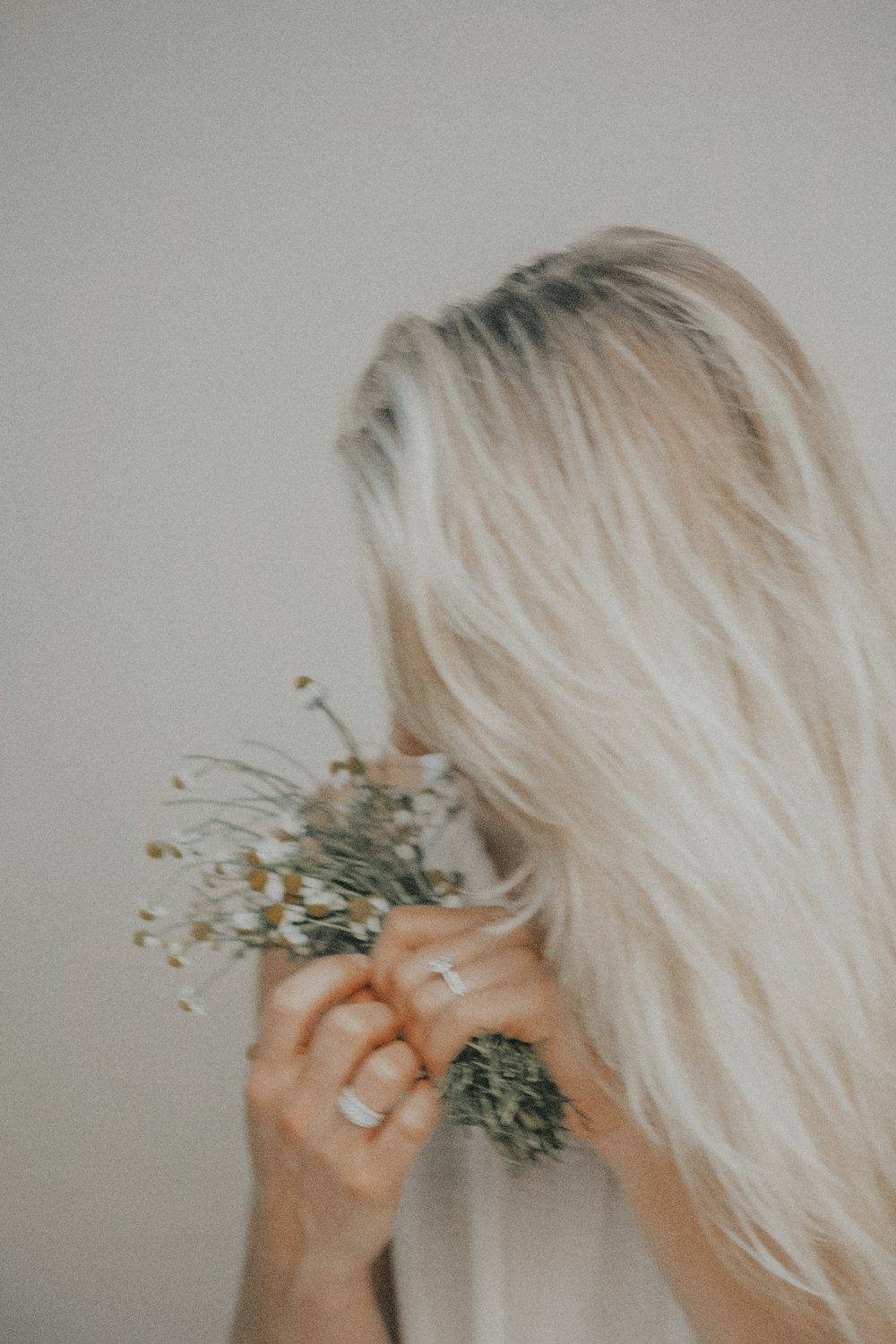 woman holding white flowers in white painted room