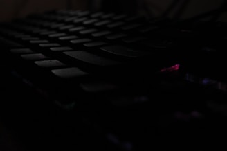 A close-up of a keyboard with a shadowy figure in the background representing cybercrime.