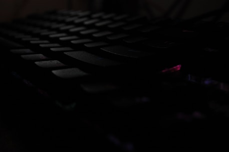 A close-up of a keyboard with a shadowy figure in the background representing cybercrime.