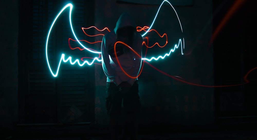 man in black jacket standing in front of neon light signage