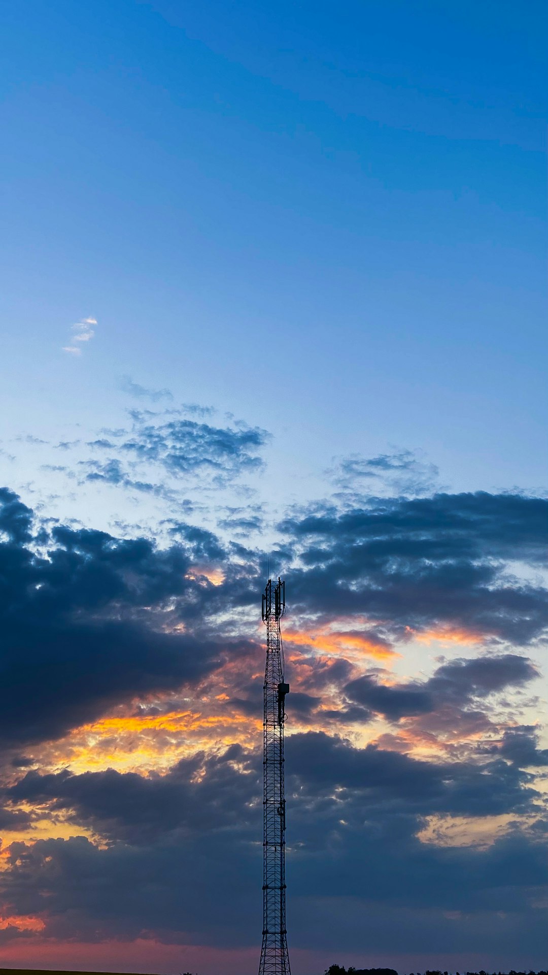 silhouette of tower under cloudy sky during sunset