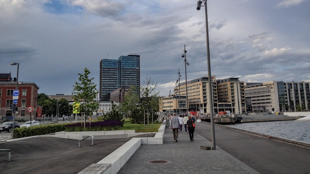 people walking on sidewalk near high rise buildings during daytime