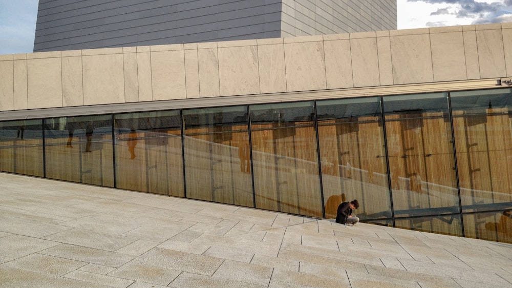 man in black jacket sitting on gray concrete floor during daytime