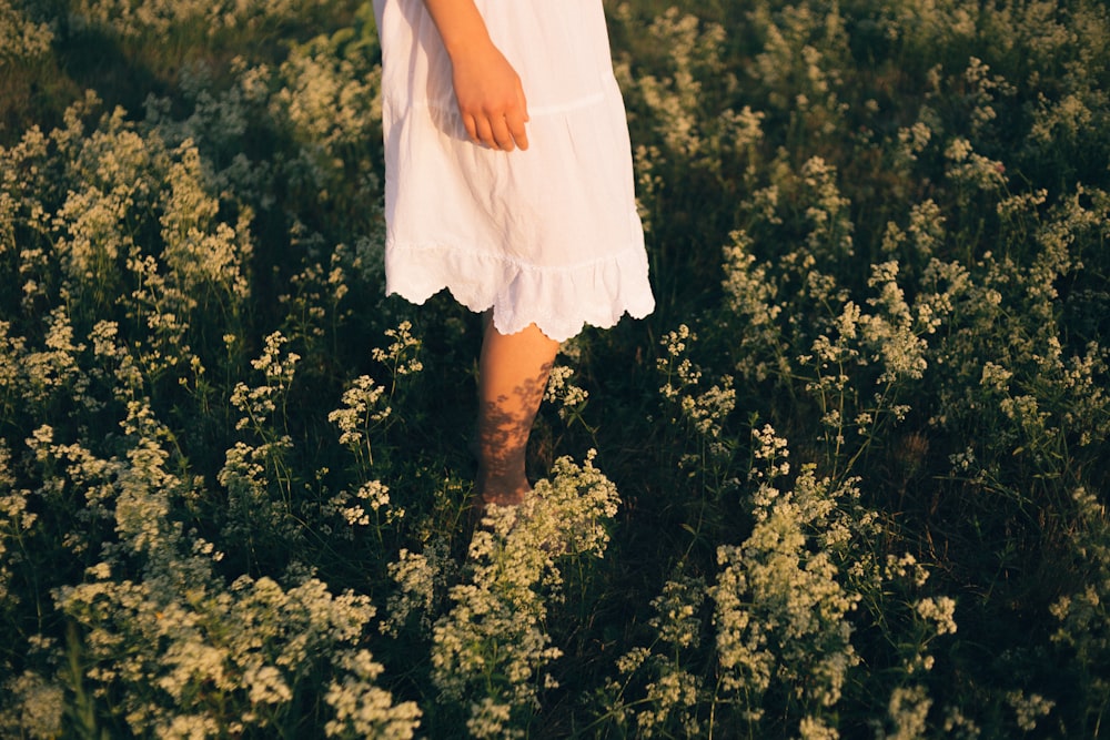 woman in white mini dress standing on green grass field during daytime