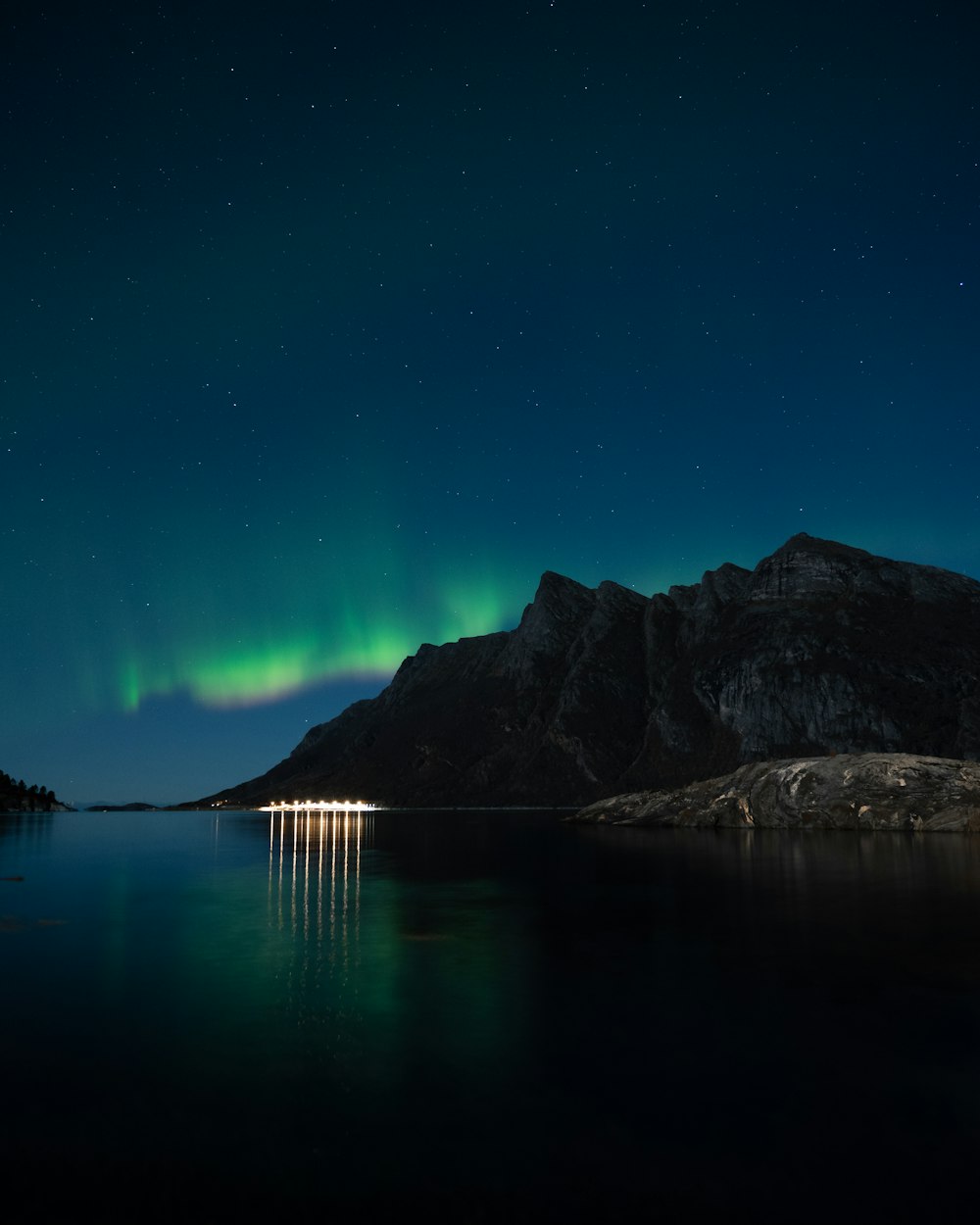 body of water near mountain during night time