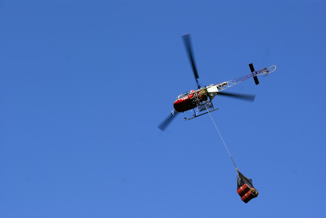 red and black helicopter flying in the sky