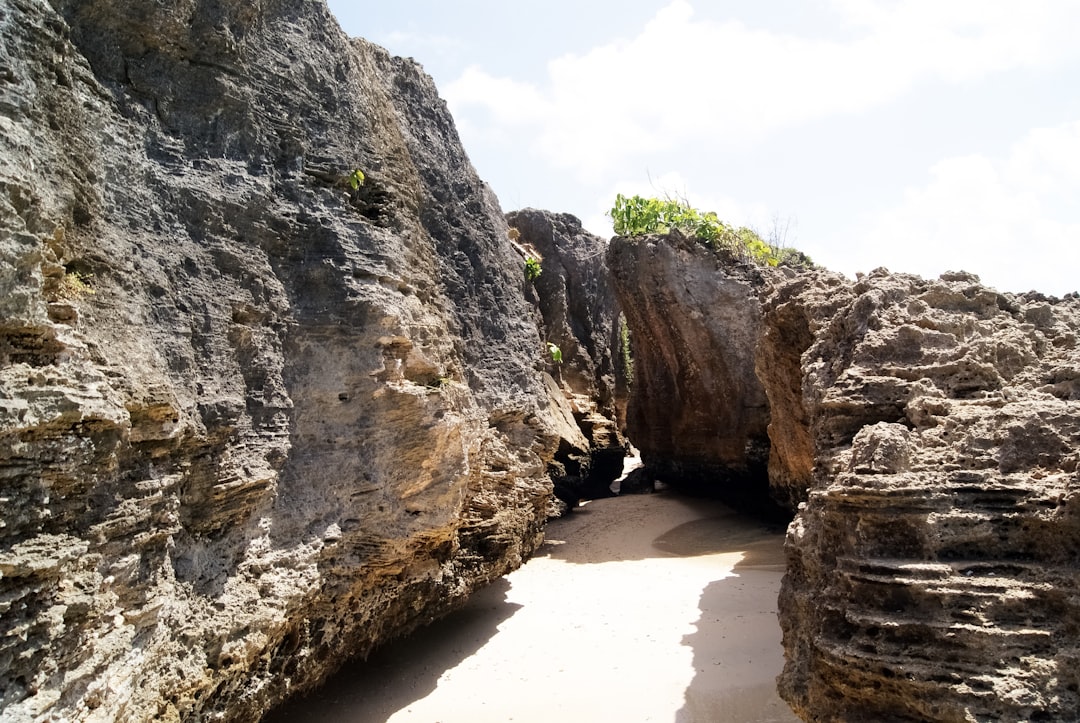 brown rock formation on white sand beach during daytime