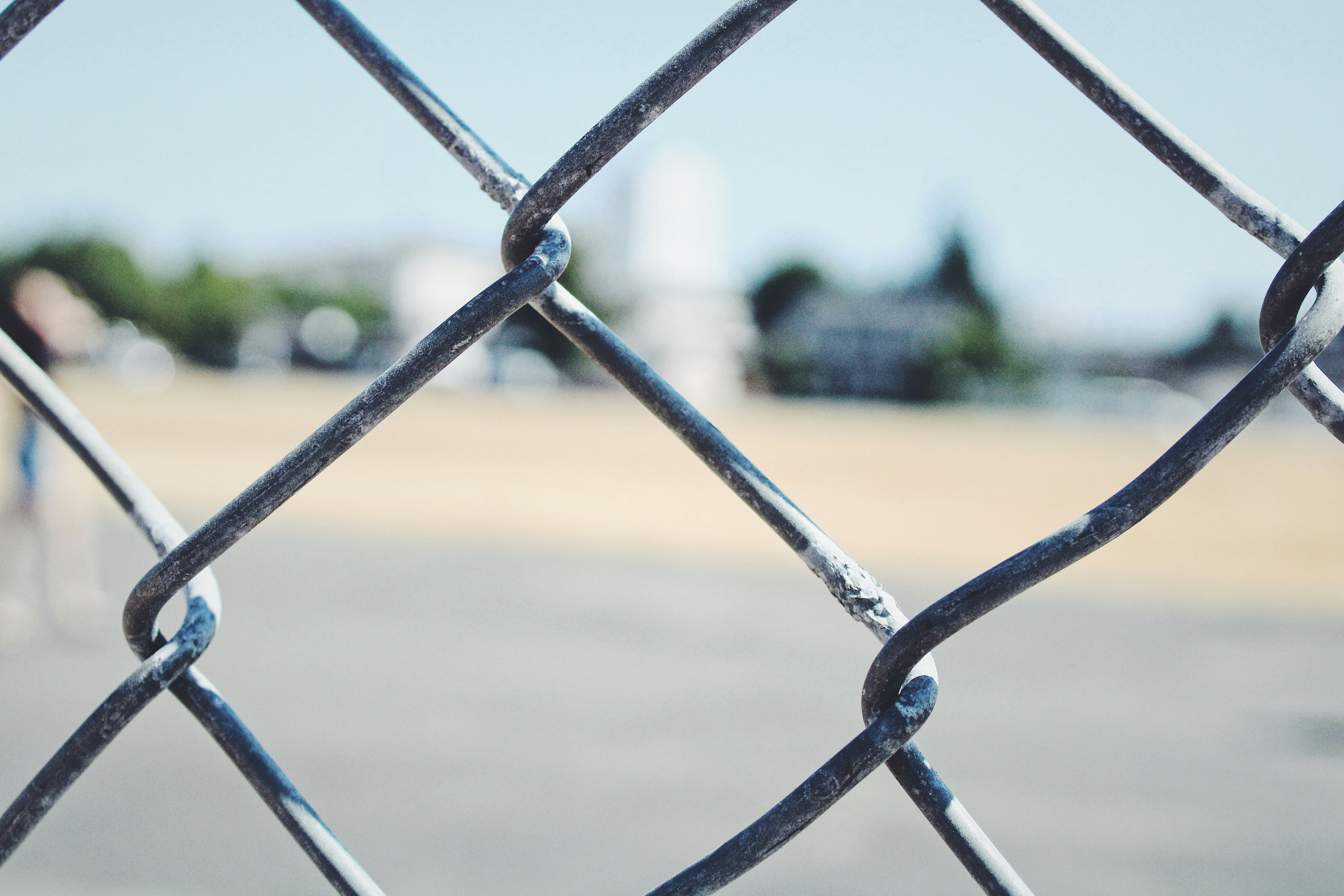 grey metal fence near green grass field during daytime