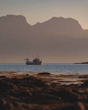 A serene view of a fishing boat at sunrise near the forested shores of Prince of Wales Island.
