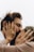 A close-up shot of two people sharing an intimate moment, with their hands gently holding each other's faces. Both individuals are wearing rings, and one has a red string bracelet on their wrist. The image conveys a sense of closeness and affection.