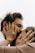 A close-up shot of two people sharing an intimate moment, with their hands gently holding each other's faces. Both individuals are wearing rings, and one has a red string bracelet on their wrist. The image conveys a sense of closeness and affection.