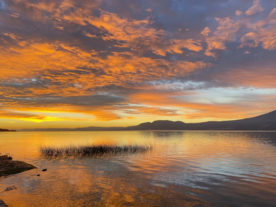 body of water under cloudy sky during sunset