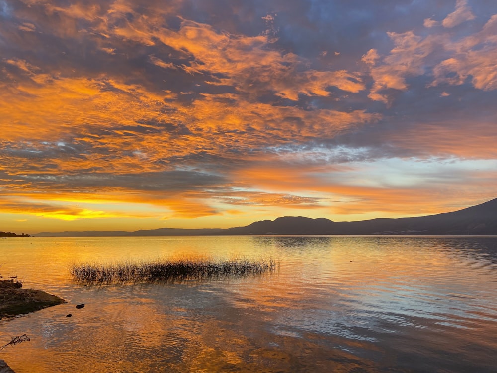 Cuerpo de agua bajo cielo nublado durante la puesta del sol