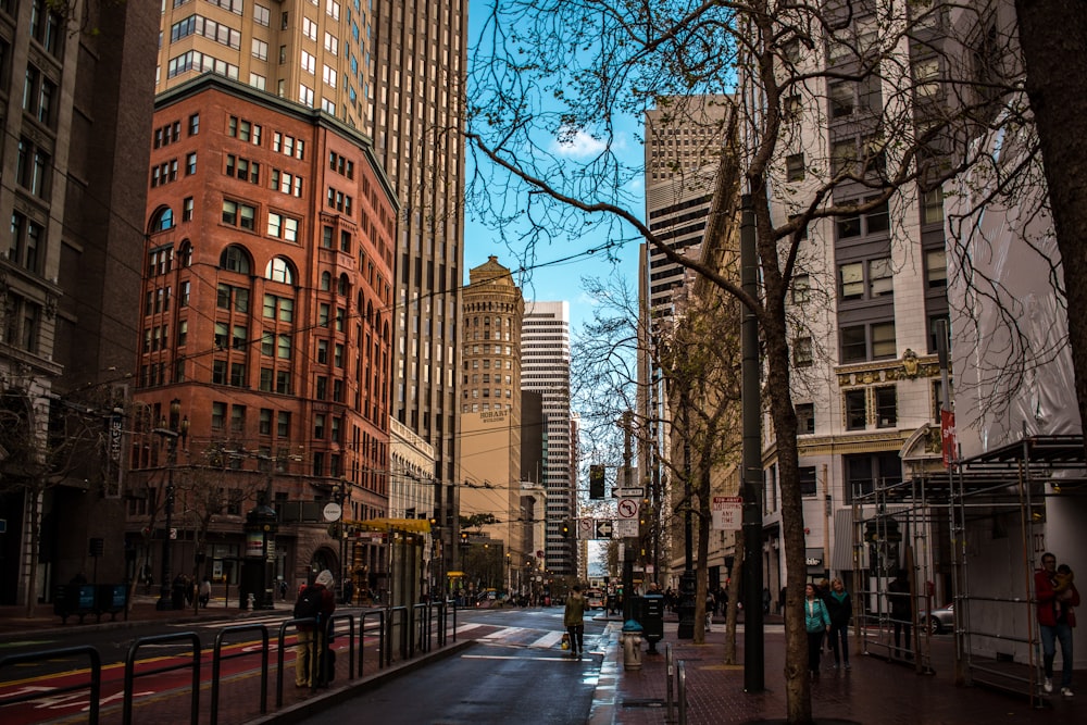 people walking on sidewalk near high rise buildings during daytime