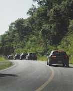 A convoy of vehicles moving along a scenic highway route.