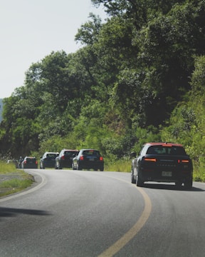 A convoy of vehicles moving along a scenic highway route.