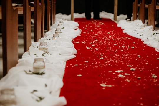 A beautifully decorated wedding aisle lined with white roses and glowing candles.