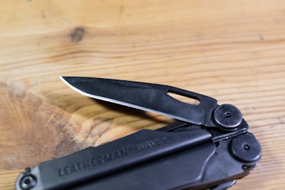 A sleek, durable multi-tool resting on a wooden workbench with natural light highlighting its details.