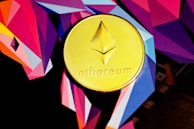 A gold coin featuring the Ethereum logo and name is set against a vibrant, geometric background with bold angular shapes in shades of purple, pink, orange, and blue.