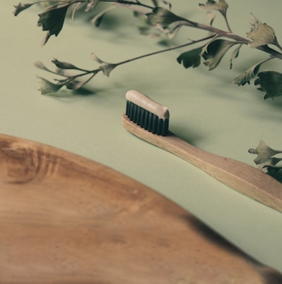 brown wooden hair comb on white and green floral textile