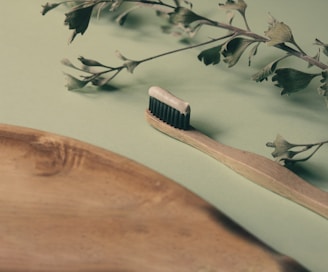 brown wooden hair comb on white and green floral textile