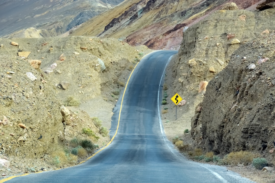 gray concrete road between rocky mountains during daytime