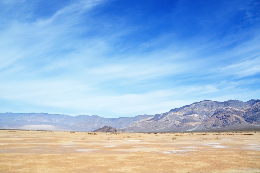 brown field near brown mountain under blue sky during daytime