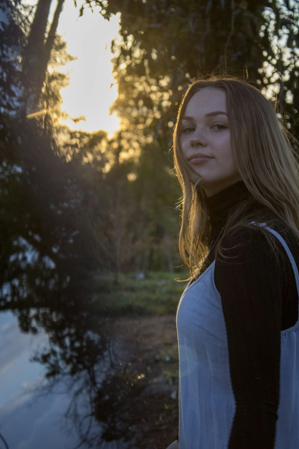 woman in black and white shirt standing near green trees during daytime