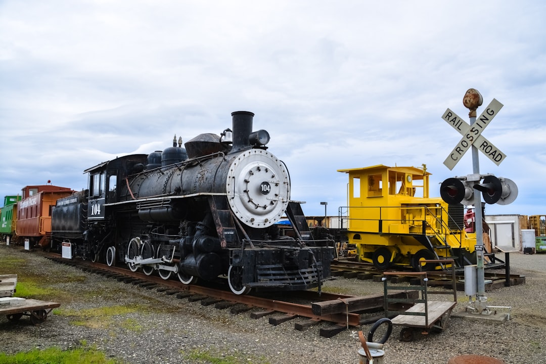 black and yellow train on rail tracks under white clouds during daytime